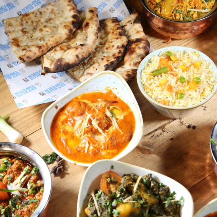A photo of curries, naans and sides